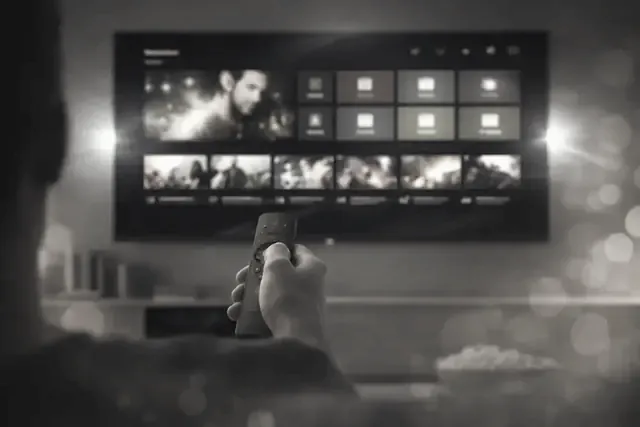A viewer pointing the remote at a player menu on a large television